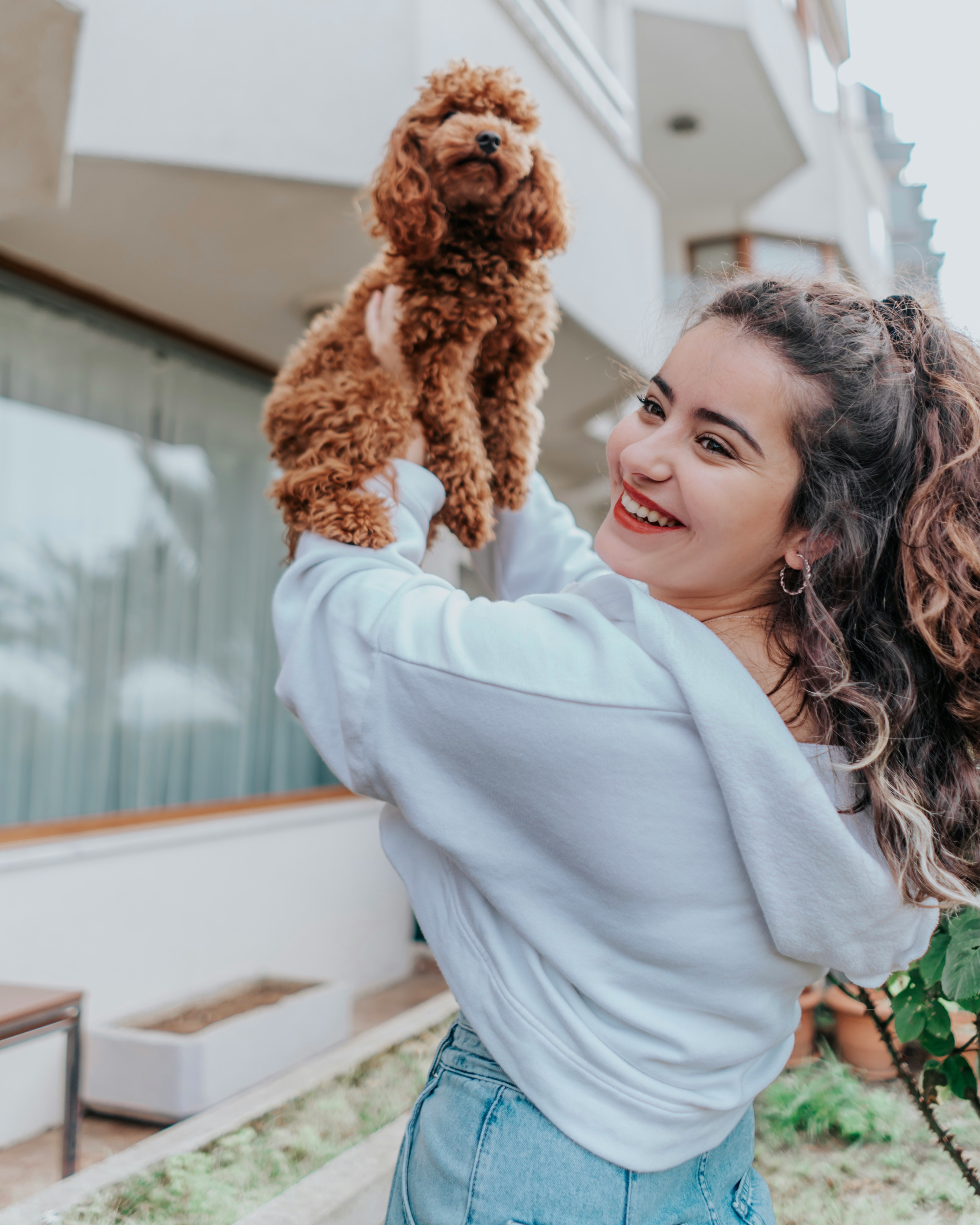 woman in white long sleeve shirt holding brown dog